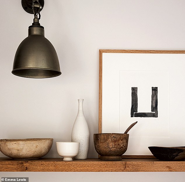 A simple wooden shelf displays monochromatic ceramics and a favourite Spencer Fung artwork. Industrial lighting adds a contemporary edge. Try skinflintdesign.com for a similar aesthetic