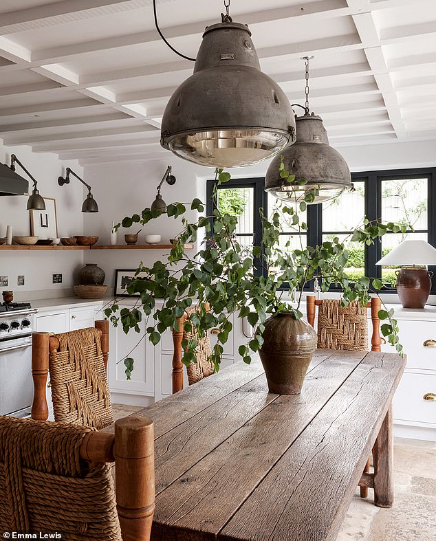 Handmade white cabinetry, a rustic dining table and industrial lighting combine to create a patina-rich kitchen. For a range of handmade wooden dining tables try woodedit.co.uk