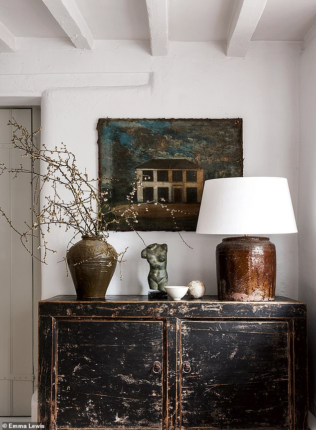 A work of 19th-century folk art is enhanced with antiques, modern ceramics and a repurposed Chinese jar turned lamp base. Black chest from Anton and K